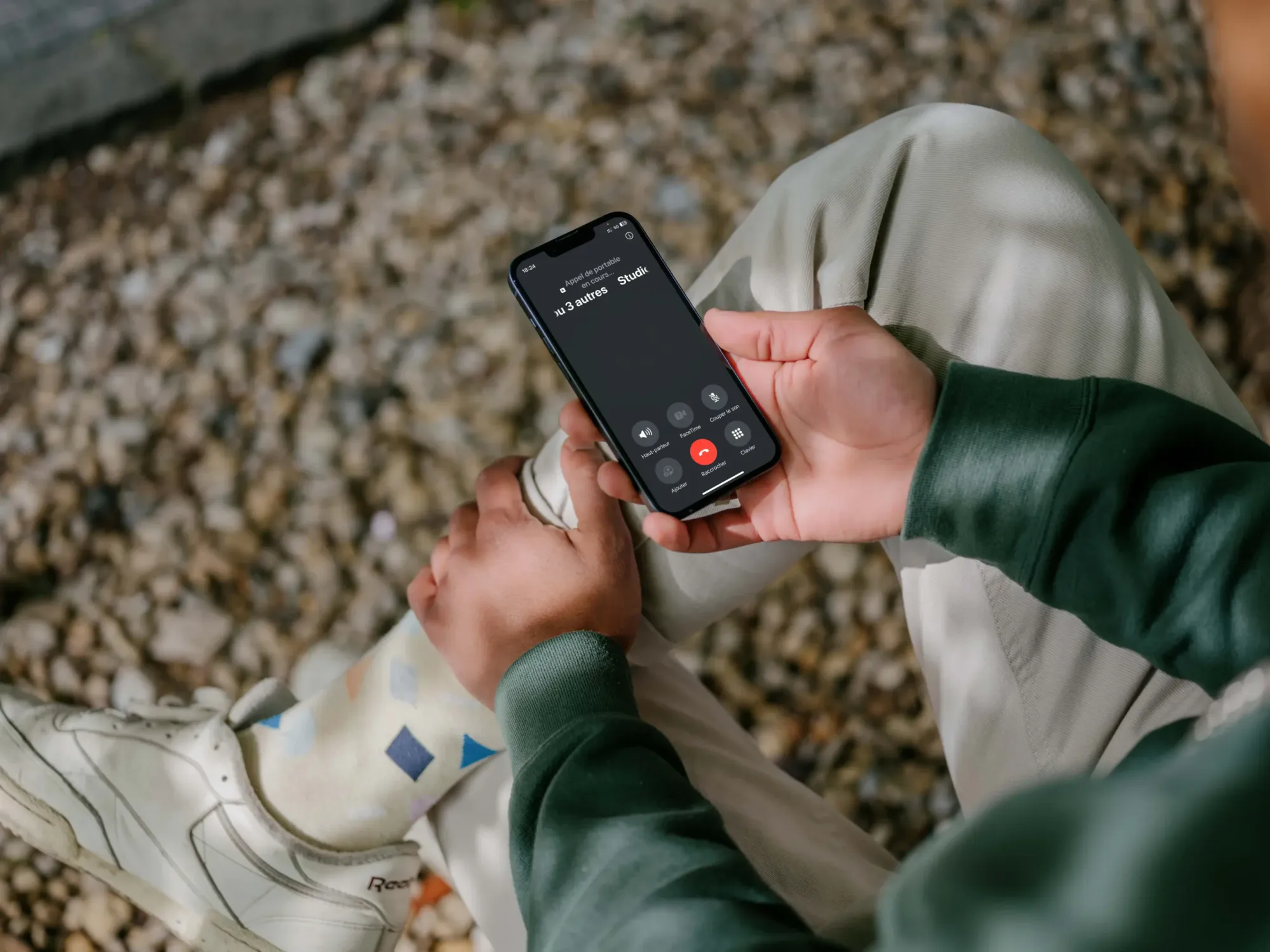 Personne assise à l'extérieur passant un appel sur son téléphone mobile